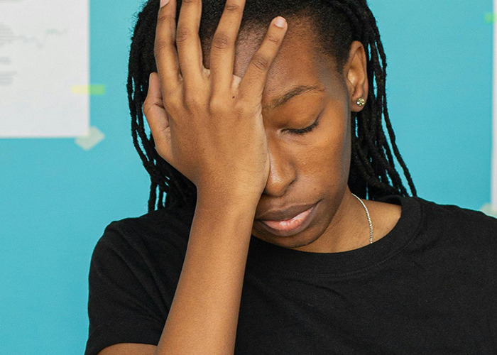 Person with dreadlocks covering face with hand, expressing frustration over horrible gifts they have actually received.