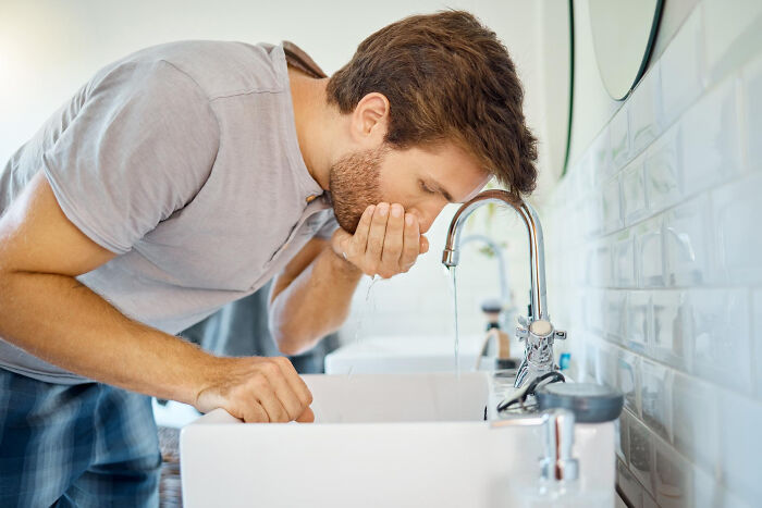 Man washing his face at a bathroom sink, showing lovable clueless dads moments during pregnancy.