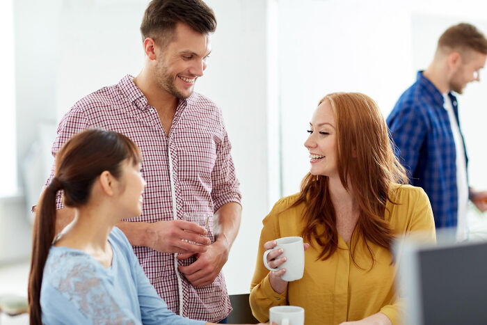 Three adults smiling and talking in an office setting, illustrating signs a child was never loved properly.