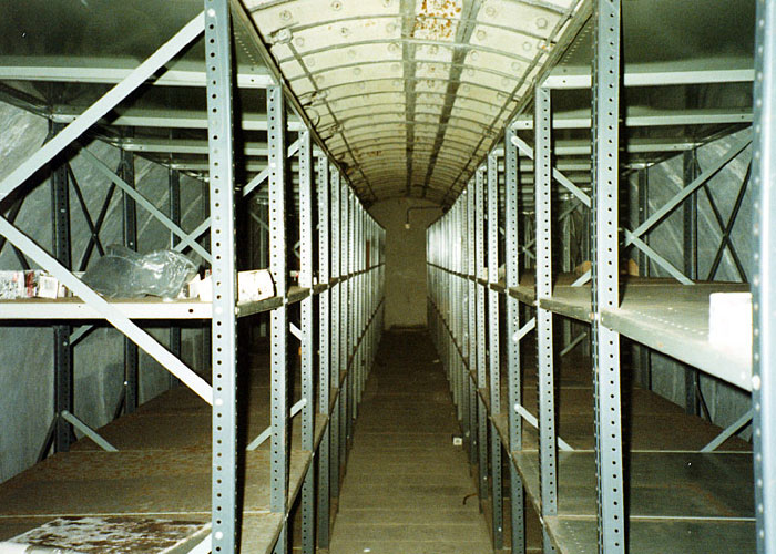 Empty metal shelves inside a narrow hidden wall space, one of the fascinating items people found in the walls of their homes.