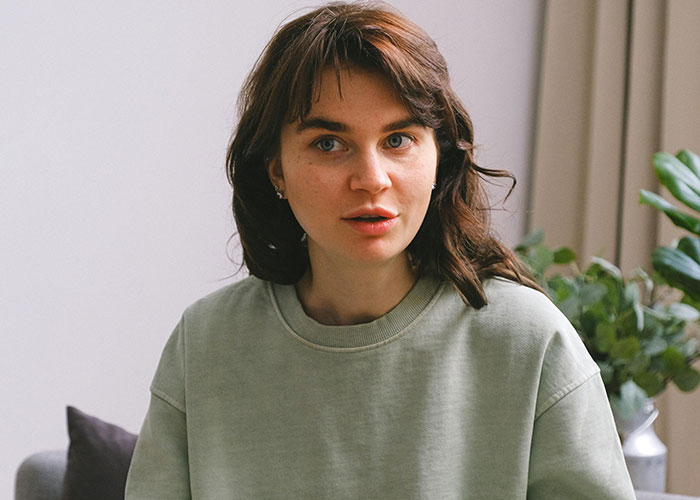 Young woman sharing useful life hacks in a cozy room with plants, surprised others haven't used them before.