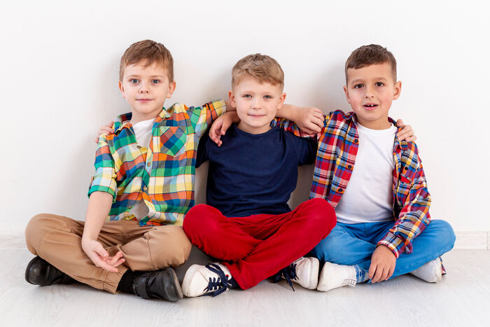 Three kids sitting on the floor with arms around each other, showing quirky and playful behavior passed down from parents.