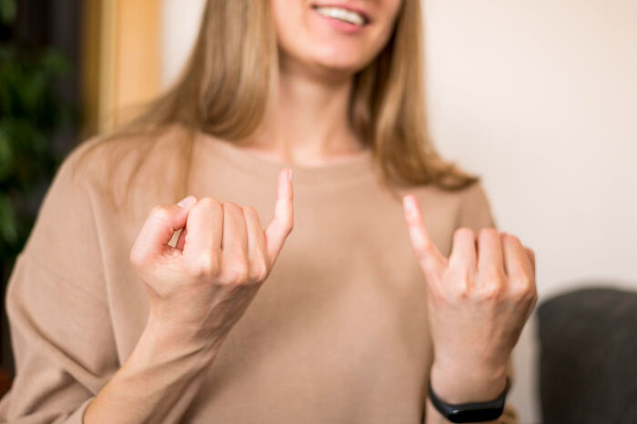 Young woman smiling while showing matching pinky promise gesture, illustrating kids doing something passed down from parents.