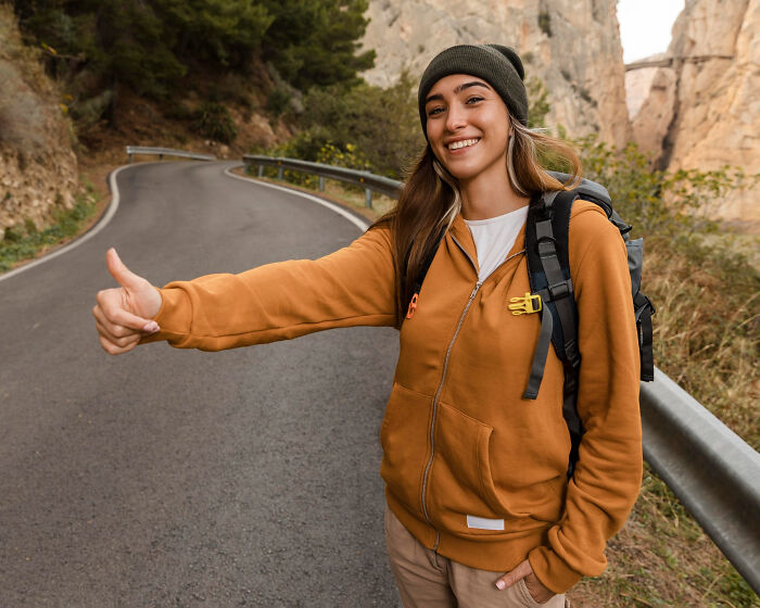 Young woman hitchhiking on a remote road symbolizing people who disappeared to start new lives and share their experiences