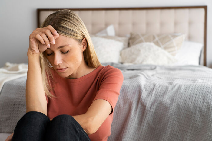 Woman sitting on floor in bedroom looking distressed, illustrating the impact of little lie backfire stories.