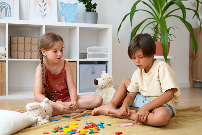 Two children sitting on the floor surrounded by colorful toys, illustrating mashed potatoes Thanksgiving arguments concept.