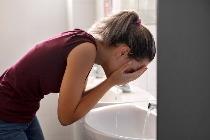 Woman in a bathroom washing her face, illustrating mysterious medical issues and the diagnoses that made it clear.