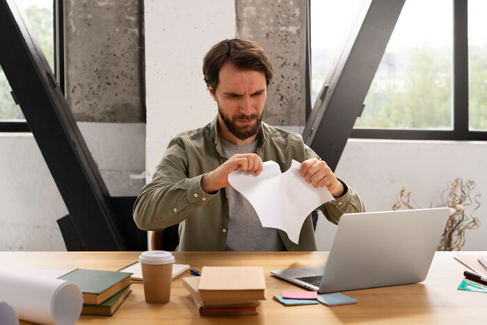 Man frustrated at desk tearing paper, illustrating stories of people who messed up once and learned their lesson.