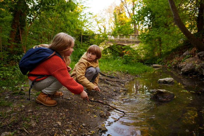 Two children by a forest stream exploring nature, illustrating a little lie that backfired in an outdoor setting.