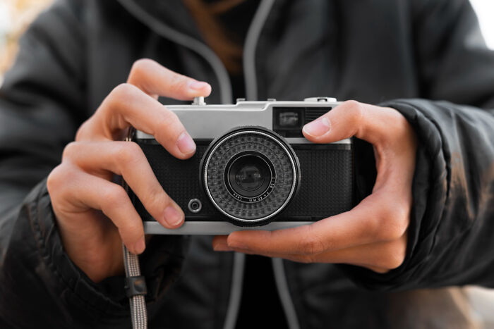Person holding a vintage camera focusing on the lens, illustrating absurd but true stories that are hard to believe.