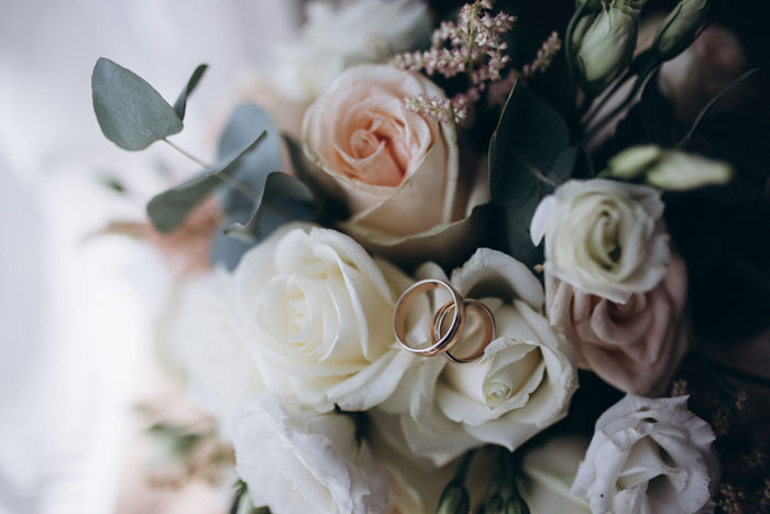 Close-up of wedding rings resting on a bouquet of roses, symbolizing family drama shared by people online.