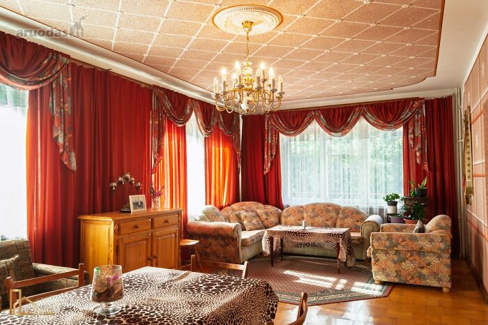 Vintage living room with floral sofas and red curtains featured in wild real estate listings showcasing unique property styles.