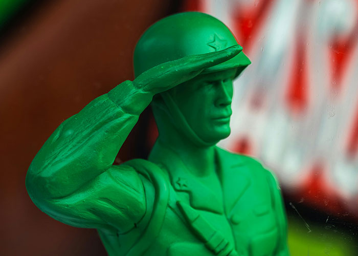 Green plastic toy soldier figurine saluting, representing one of the fascinating items people found in the walls of their homes.