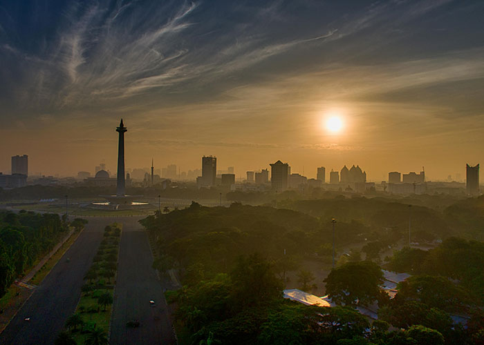 A city skyline at sunrise with trees and wide roads, illustrating one of the worst cities worldwide you should never visit.