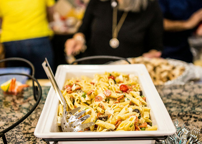 Close-up of a pasta dish at a buffet where people are sharing life hacks that others don’t use in a casual setting.