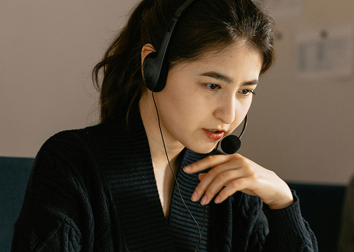 Young woman wearing a headset, focused on her computer screen while exploring terrifying things found online.