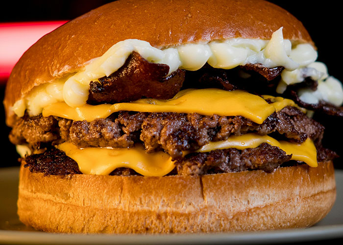 Close-up of a cheeseburger with multiple beef patties and melted cheese, illustrating fascinating items found in walls.