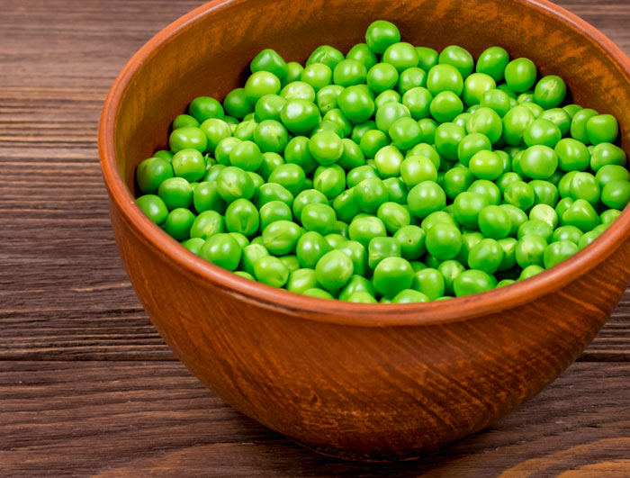 Bowl of fresh green peas on a wooden table representing man picking at his food during dinner with mom’s boss. Bowl of fresh green peas on a wooden table representing man picking at his food during dinner with mom’s boss.