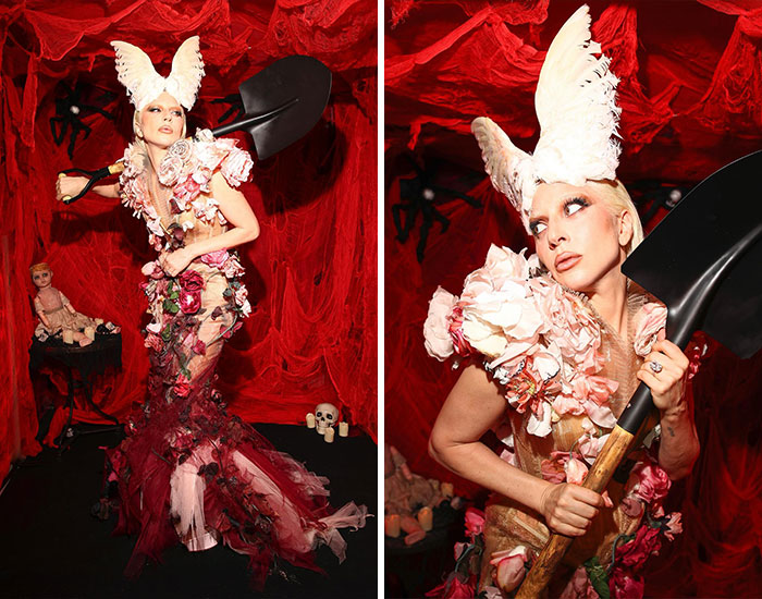 Celebrity wearing an elaborate Halloween costume with floral details and a white feathered headpiece, holding a shovel.