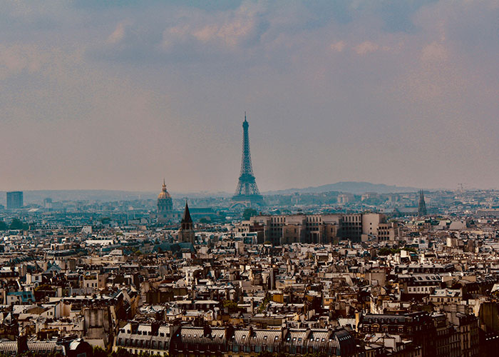 Panoramic view of a large city skyline with the Eiffel Tower under a cloudy sky, highlighting worst cities worldwide.