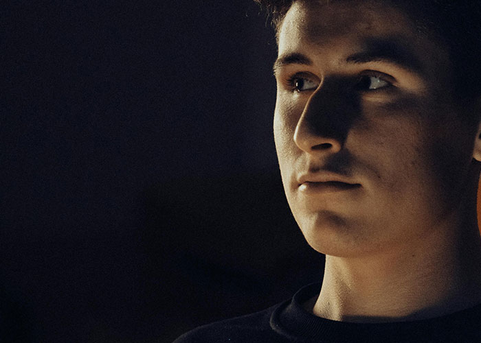 Young man in low light with a serious expression reflecting on bizarre events that creeped people out.