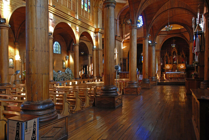 Interior of a wooden church with tall columns and pews, creating a peaceful and historic atmosphere.