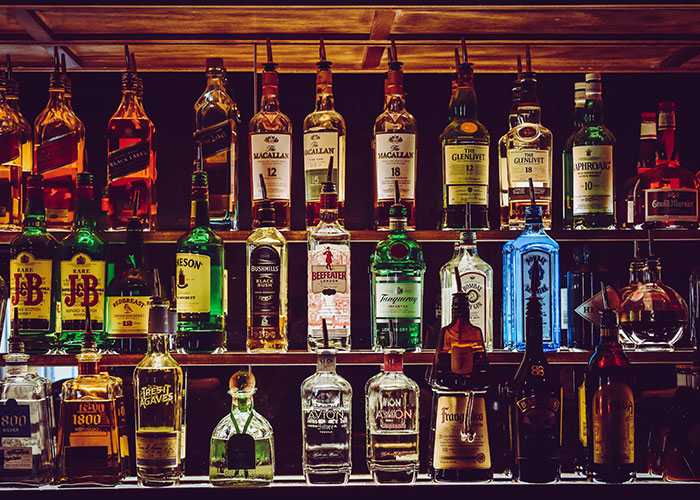 Shelf of assorted whiskey and liquor bottles in a bar setting illustrating common knowledge people realized wasn’t so common.