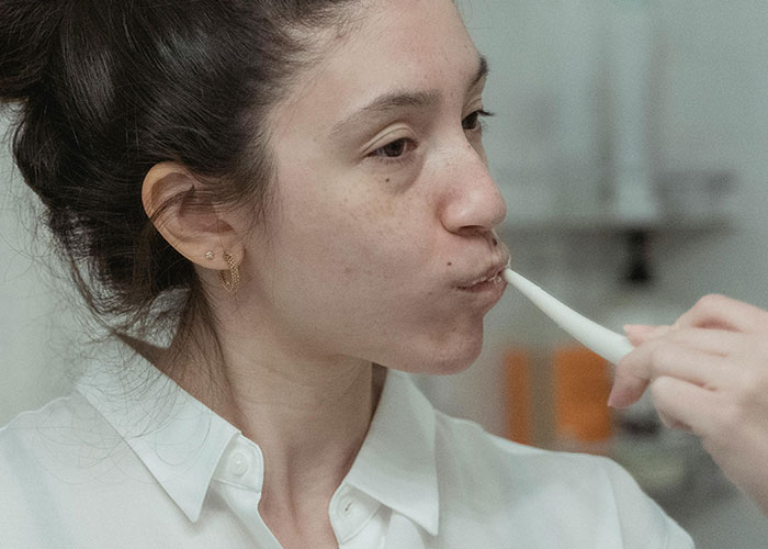 Woman demonstrating a life hack by using an electric toothbrush in a simple daily routine for better personal care.