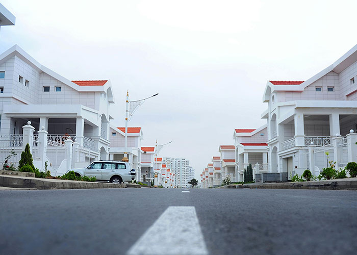 Residential street with white houses and parked cars, representing one of the worst cities worldwide to avoid visiting.