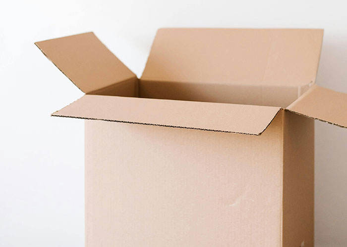 Open empty cardboard box with flaps unfolded, illustrating genius cleaning hacks inspired by laziness.