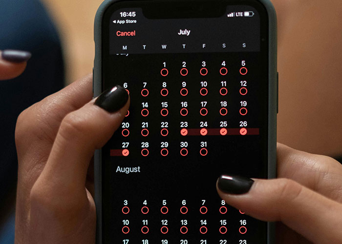 Hands holding smartphone showing calendar app with life hacks calendar marked for easy organization and planning.