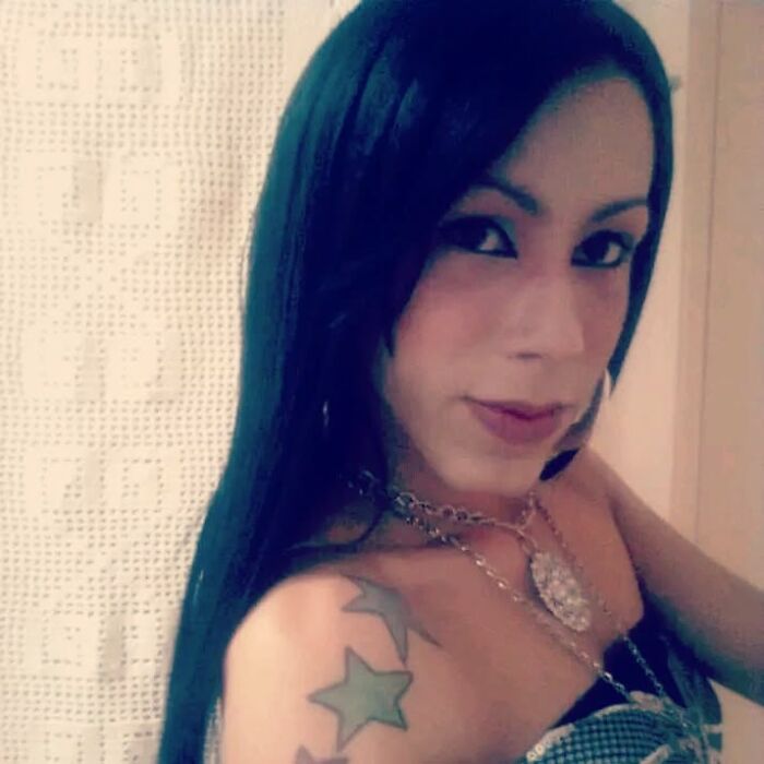 Influencer with visible tattoo posing indoors after undergoing botched plastic surgery and new restorative operation.