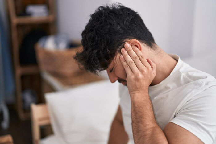 Man holding his head in pain indoors, representing people sharing mysterious medical issues and clear diagnoses.