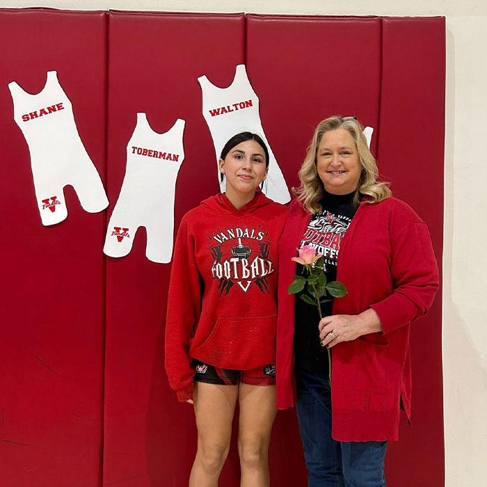 Two women standing in gym with wrestling singlets on wall, unrelated to step-uncle arrested after body of 14YO girl found in RV. Two women standing in gym with wrestling singlets on wall, unrelated to step-uncle arrested after body of 14YO girl found in RV.