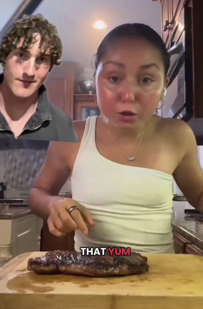 Woman in kitchen presenting wild American food creation on wooden board with steak, reacting to the taste, internet food trends Woman in kitchen presenting wild American food creation on wooden board with steak, reacting to the taste, internet food trends