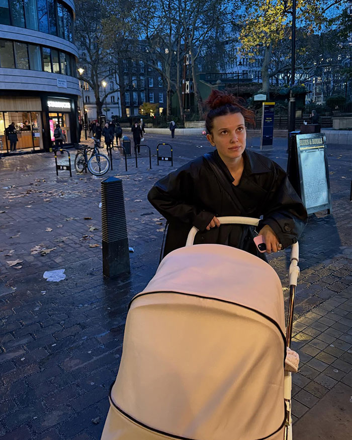 Millie Bobby Brown pushing a stroller outdoors in the evening amid fans furious over her legal name change news.