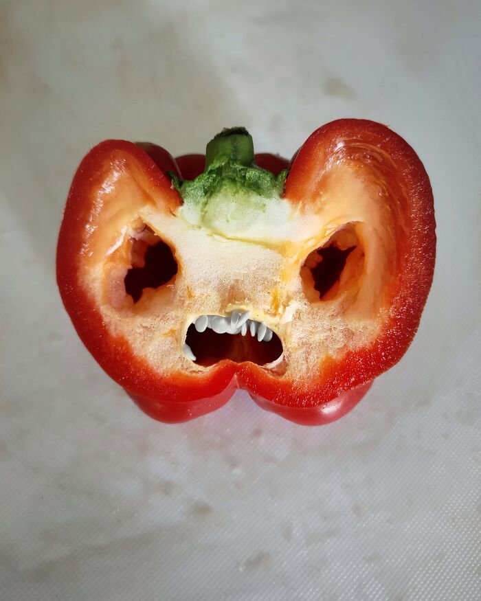 Half of a red bell pepper resembling an angry face with teeth, showing an object that unintentionally resembles something else.