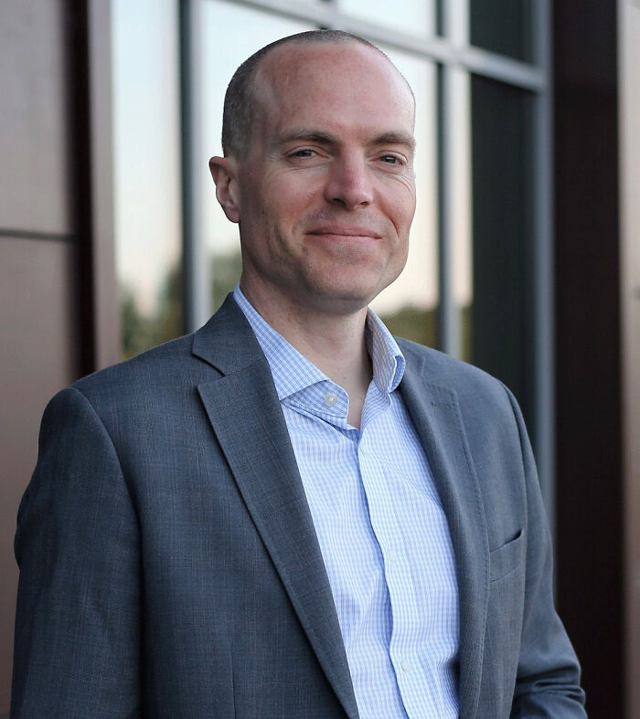 Man in a gray suit standing outside a building, related to father and son tragic incident while zip-lining.