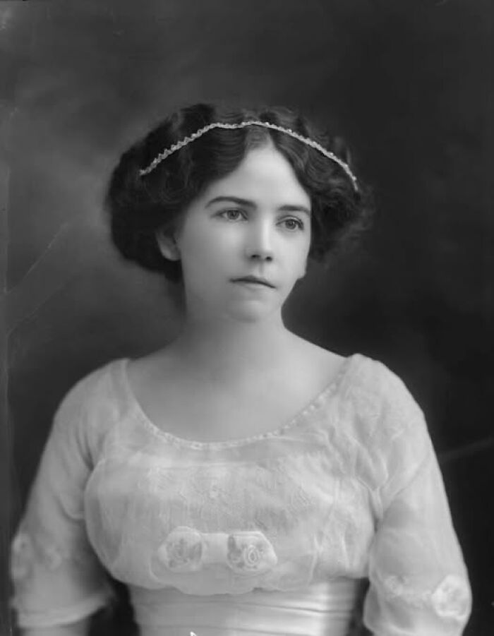 Young woman in Victorian Edwardian style dress and hairstyle posing for a classic black and white formal portrait photograph