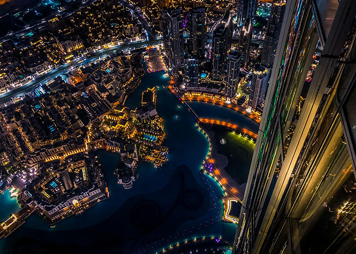 Aerial night view of city lights and buildings reflecting on a river in one of the worst cities worldwide to visit.