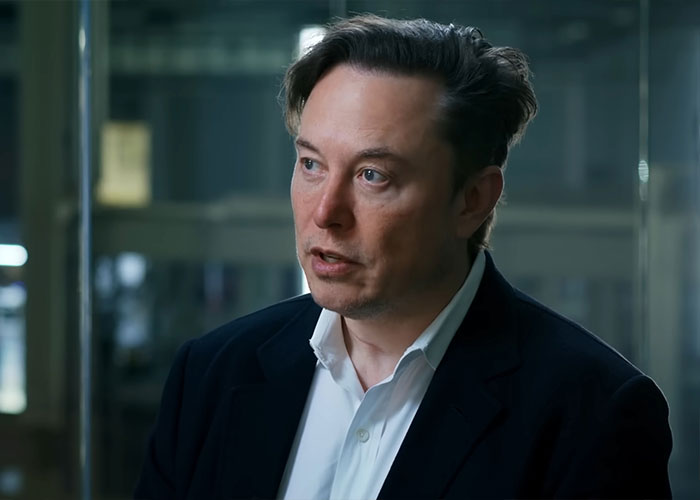 Elon Musk in a dark suit and white shirt speaking during an interview about Joyce Carol Oates&rsquo; uncultured comment.