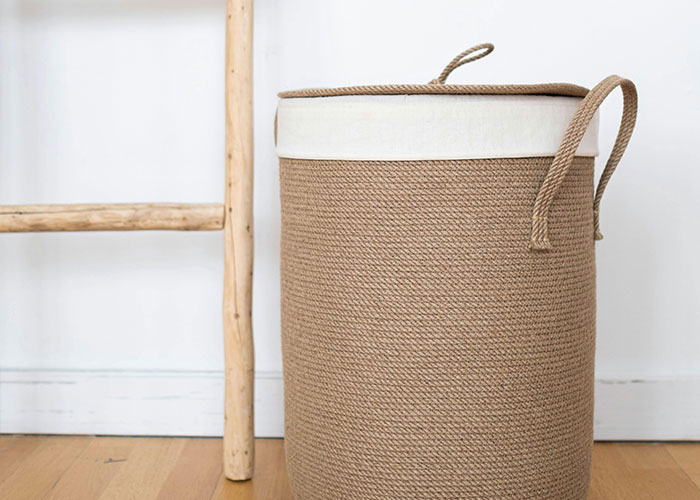 Large woven basket with handles next to a wooden ladder, illustrating genius cleaning hacks inspired by laziness.