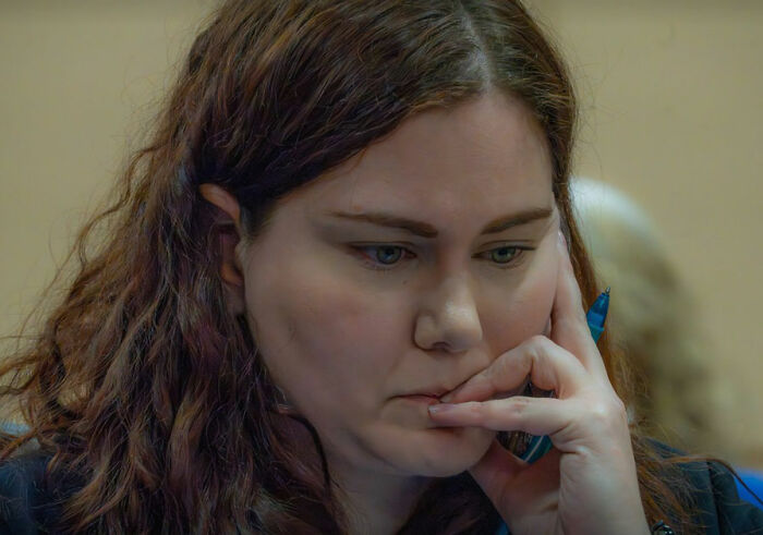 Woman with red hair holding a pen, deep in thought during a court case about a fatal Alaska attack. Woman with red hair holding a pen, deep in thought during a court case about a fatal Alaska attack.
