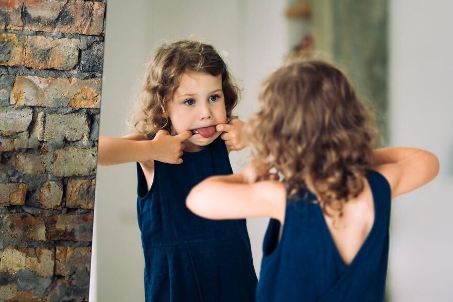 Young girl in a blue dress making a funny face in front of a mirror, embodying tongue twisters challenge playfully. Young girl in a blue dress making a funny face in front of a mirror, embodying tongue twisters challenge playfully.