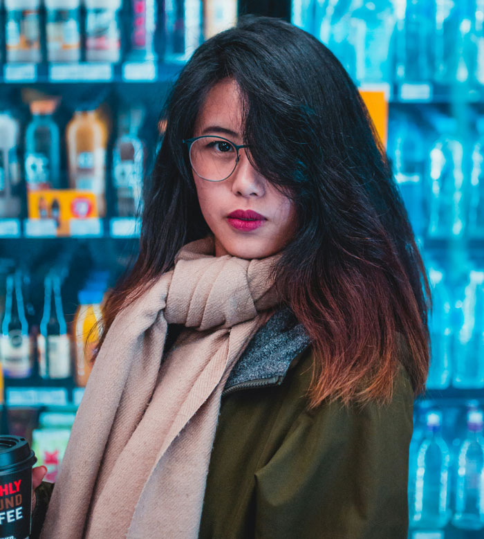 Young woman with glasses and scarf holding coffee, representing women sharing important girl code rules.