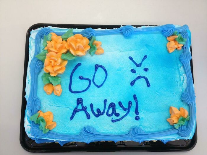 Blue frosted cake with orange flowers and the prank message Go Away, showcasing employee jokes and pranks.