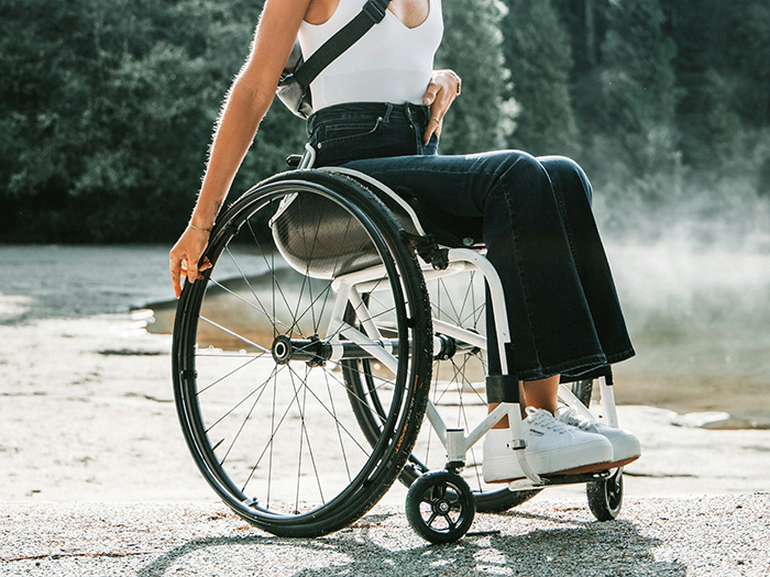 Disabled woman in a wheelchair outdoors, highlighting Disneyland security questions about her service dog use.
