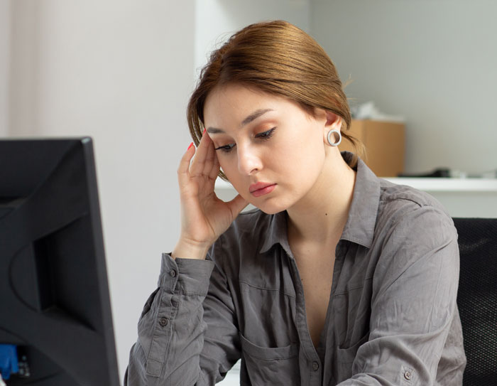 Woman at office desk looking stressed, reflecting the impact of eating what she shouldn't on a coworker.