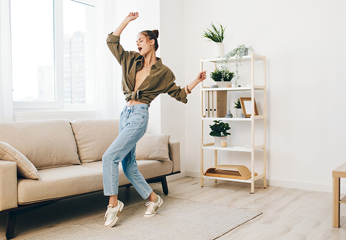 Young woman sharing inspiring update dancing joyfully in bright living room after leaving cheating husband. Young woman sharing inspiring update dancing joyfully in bright living room after leaving cheating husband.