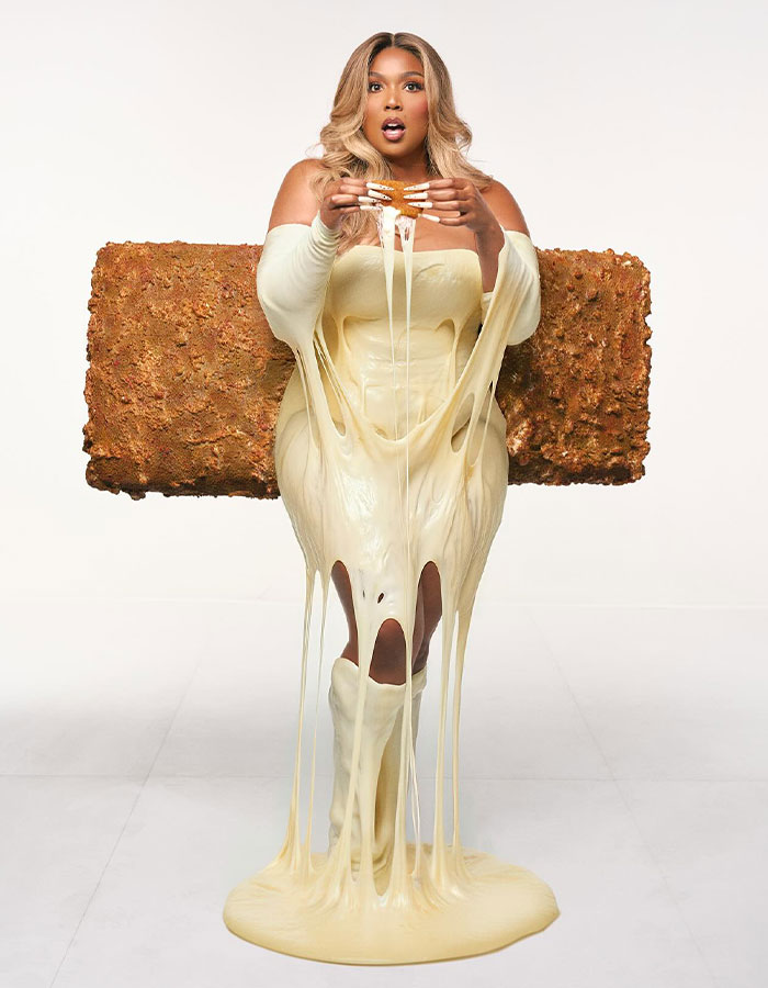 Celebrity in a creative Halloween costume resembling a giant melted cheese snack bar with gooey stretching cheese.